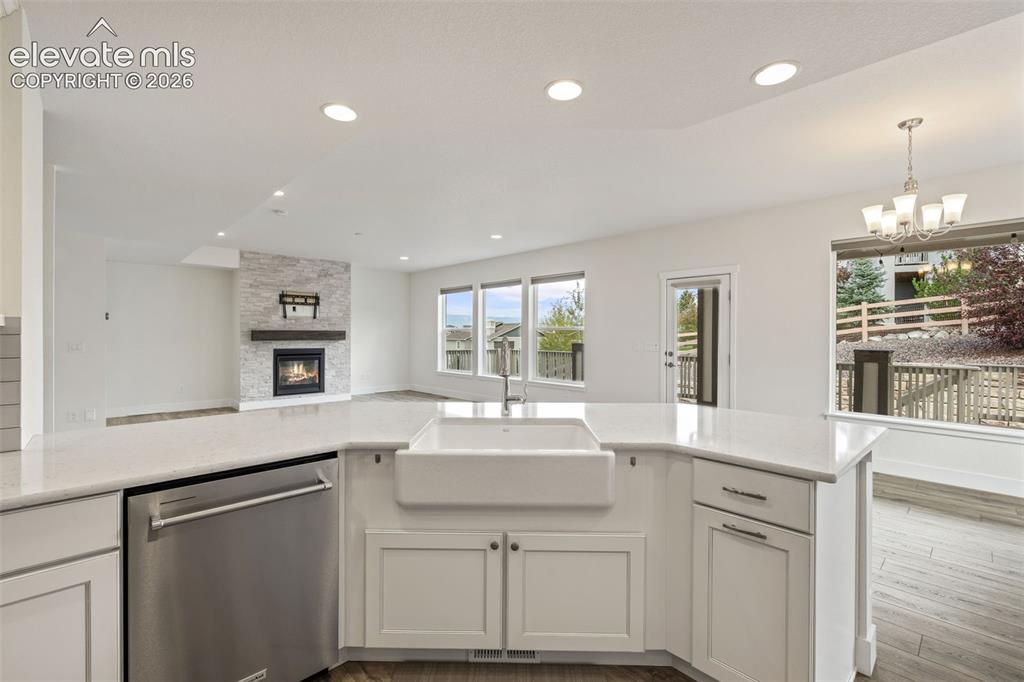 Image 17 of 50: White kitchen island with a farmhouse sink, stainless steel dishwasher, and