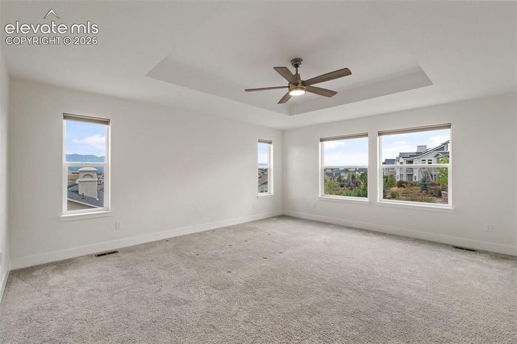 Image 21 of 50: Recessed ceiling with a central fan, light gray carpeting, and mountain vie