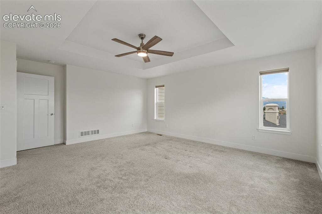 Image 24 of 50: Recessed ceiling with an integrated ceiling fan, light gray carpeting, and
