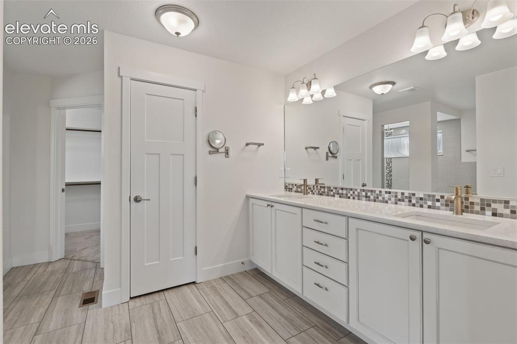 Image 25 of 50: Dual vanity with undermount sinks, wood-finish tile flooring, recessed buil