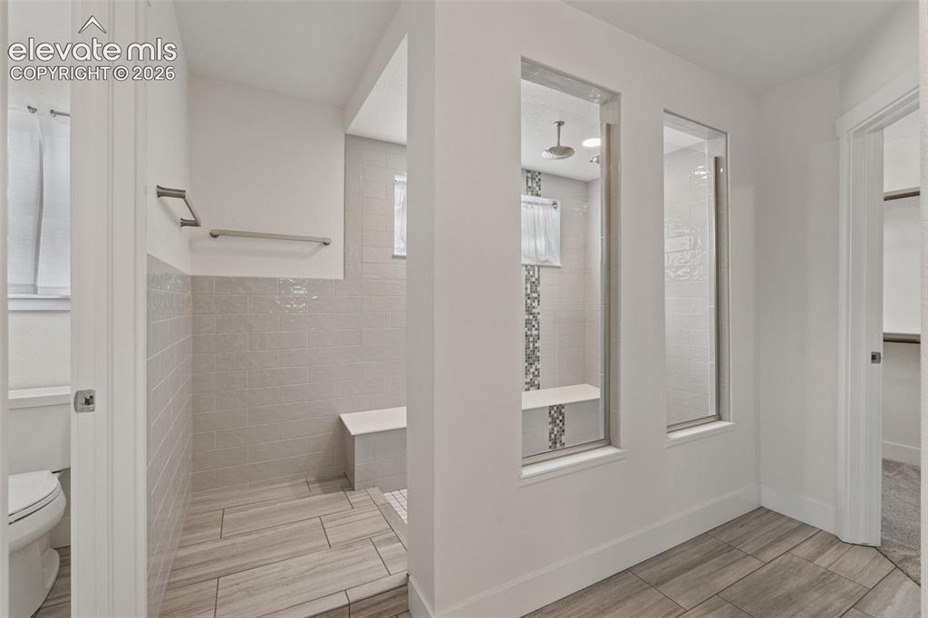 Image 26 of 50: Spa-style walk-in shower with tiled walls and flooring