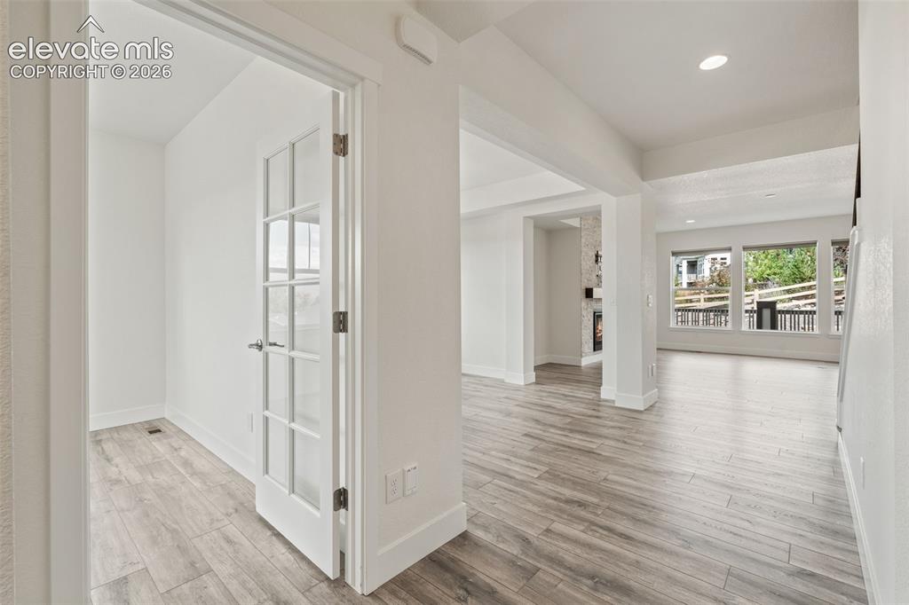 Image 3 of 50: Wood-finish LVP flooring, recessed lighting, and a glass-paneled interior d