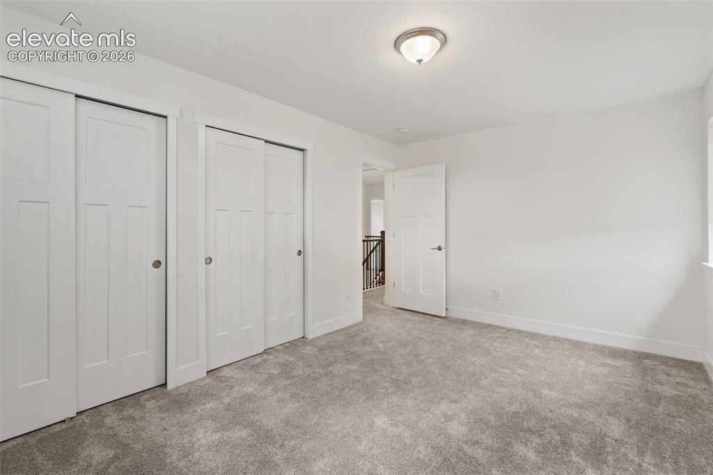 Image 30 of 50: Neutral color palette with gray carpeting, two sliding panel doors, and a c