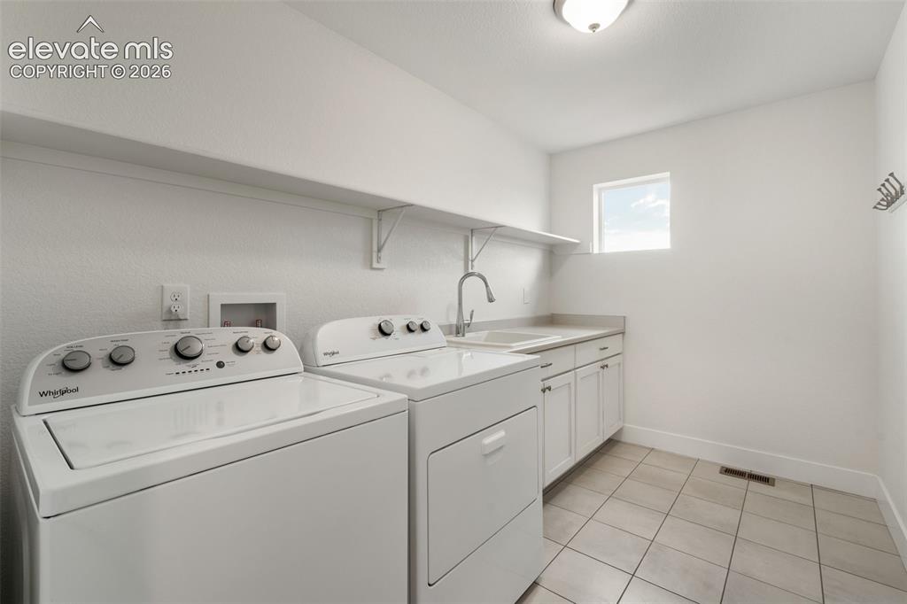 Image 33 of 50: Laundry room featuring white shaker cabinetry, an integrated utility sink, 