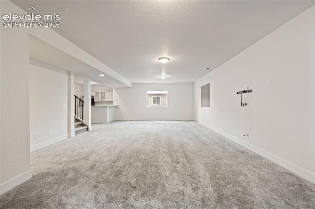 Image 37 of 50: Expansive open-concept room with gray carpet, recessed lighting, a window,