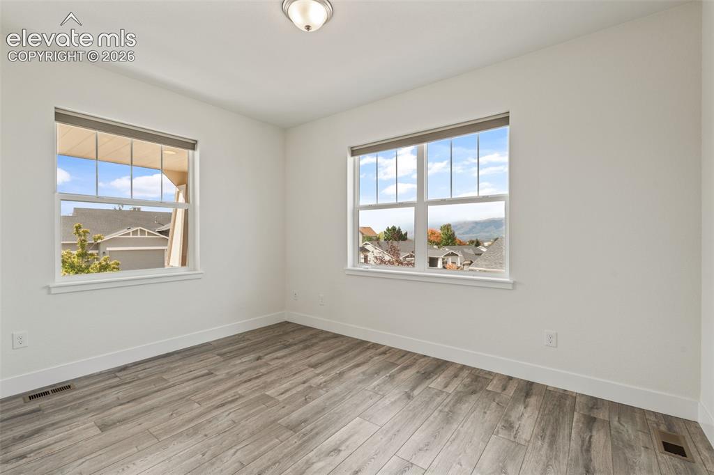 Image 4 of 50: Bright interior with two windows, wood-finish LVP flooring, and mountain v