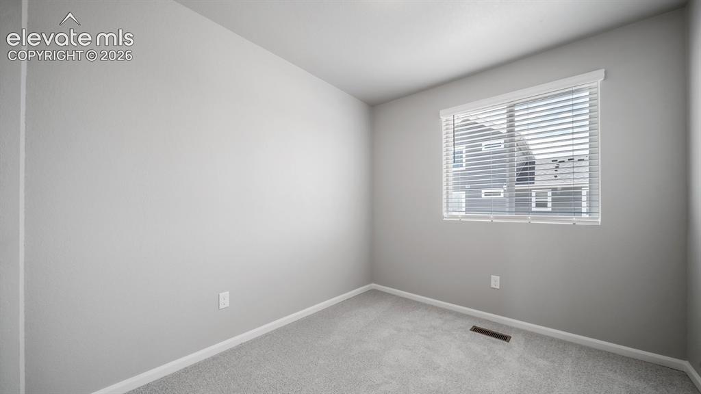 Image 12 of 28: Neutral-toned room featuring a single window with blinds, light gray wall p