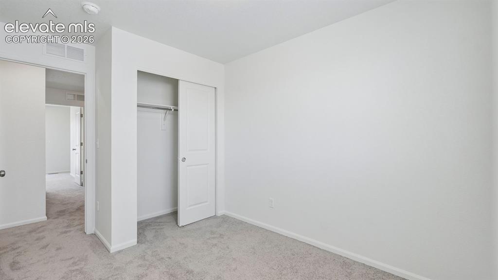 Image 12 of 28: Neutral wall color, carpet flooring, sliding closet doors, built-in closet