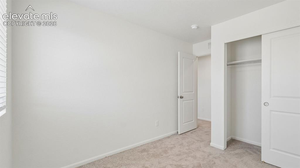Image 13 of 28: Wall-to-wall carpeting, window with blinds, bi-fold closet doors, and inter