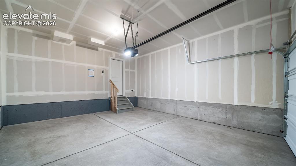 Image 14 of 28: Spacious garage with unfinished drywall, a concrete floor, and an overhead