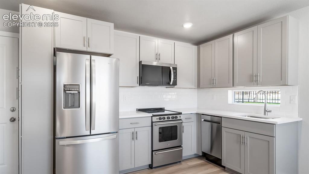 Image 15 of 28: Modern kitchen featuring gray shaker-style cabinetry, stainless steel appli