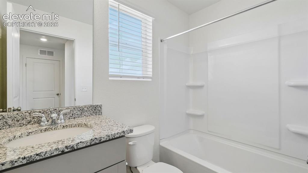 Image 17 of 28: Vanity with a polished chrome faucet, under-mount sink, and speckled counte