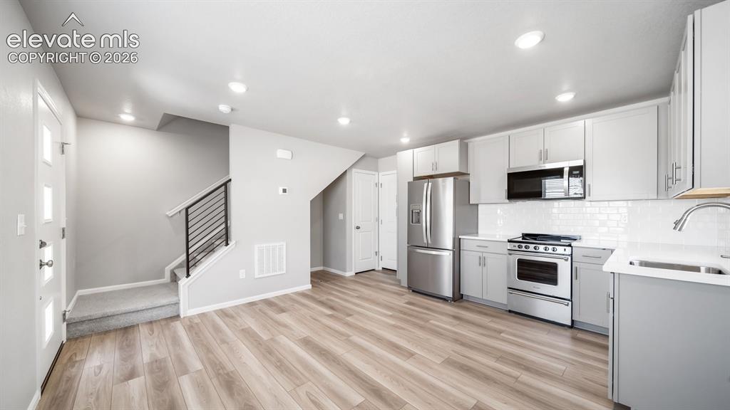 Image 18 of 28: Open-concept living space featuring wood-finish flooring, recessed lighting