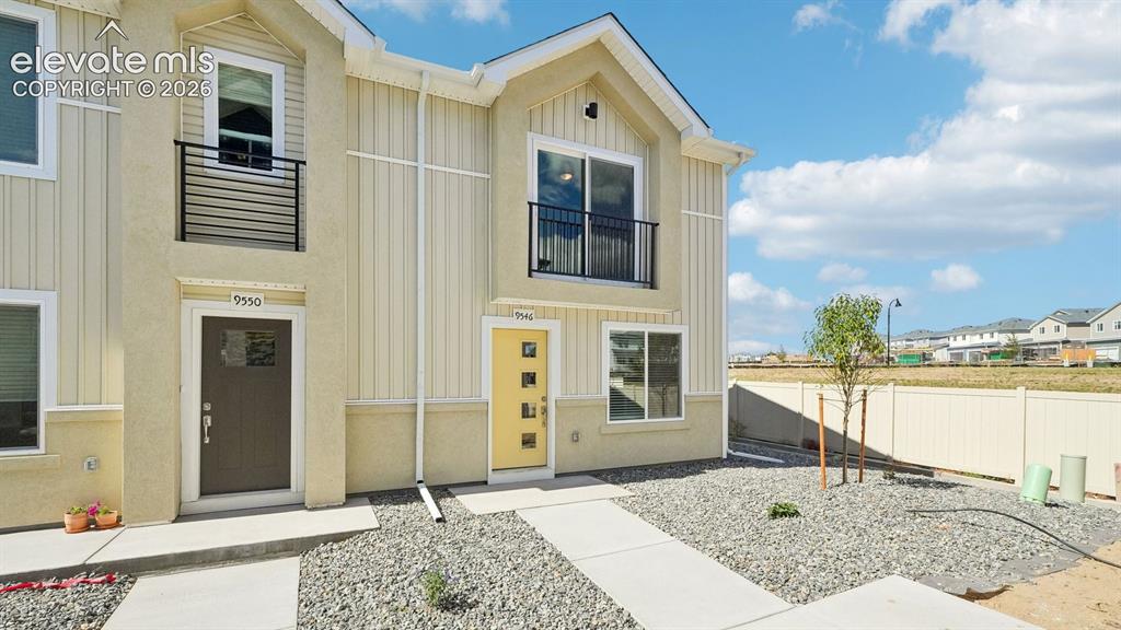 Image 2 of 28: Two-story facade with vertical siding accents and stucco, featuring a balco