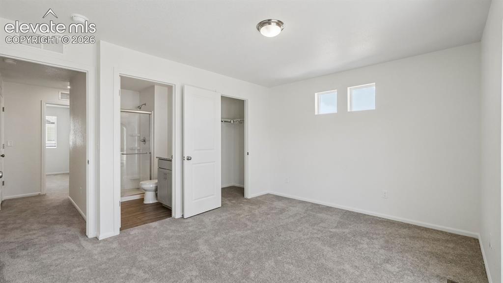 Image 20 of 28: Plush gray carpeting, white painted walls, two rectangular high windows, an