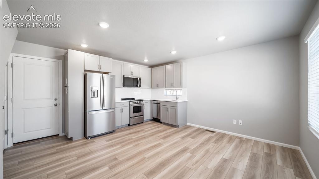 Image 21 of 28: Modern kitchen featuring stainless steel appliances, light wood-finish floo
