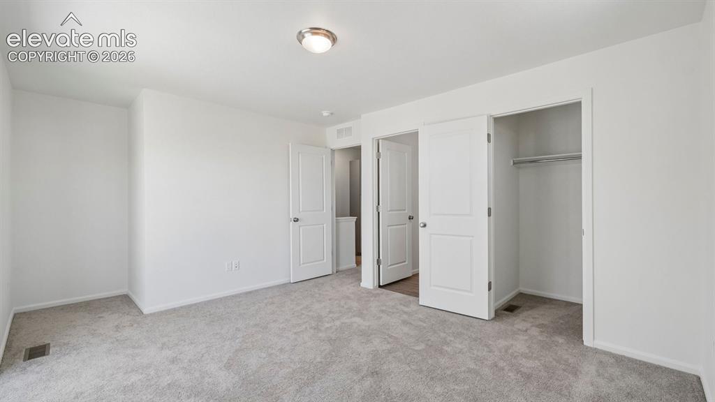 Image 21 of 28: Plush grey carpeting, white interior doors, and a built-in closet with hang