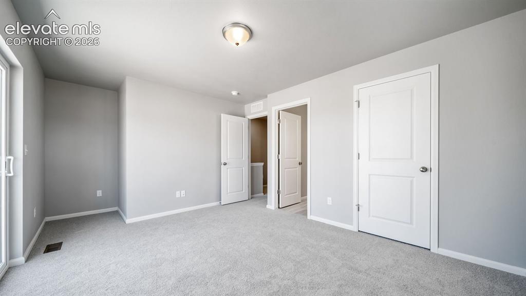 Image 23 of 28: Spacious room featuring light gray walls, plush gray carpeting, white baseb