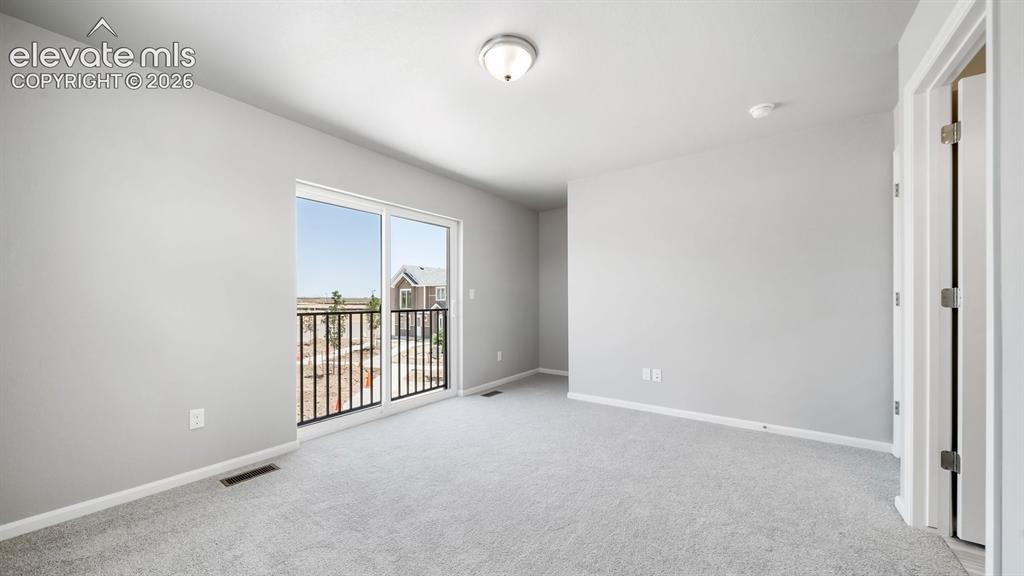 Image 24 of 28: Spacious room featuring light gray carpeting, a sliding glass door opening