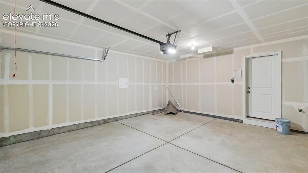 Image 25 of 28: Spacious garage featuring concrete flooring and a paneled white door
