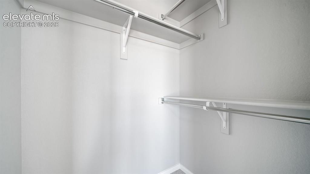 Image 26 of 28: Interior closet with white shelving and chrome hanging rods