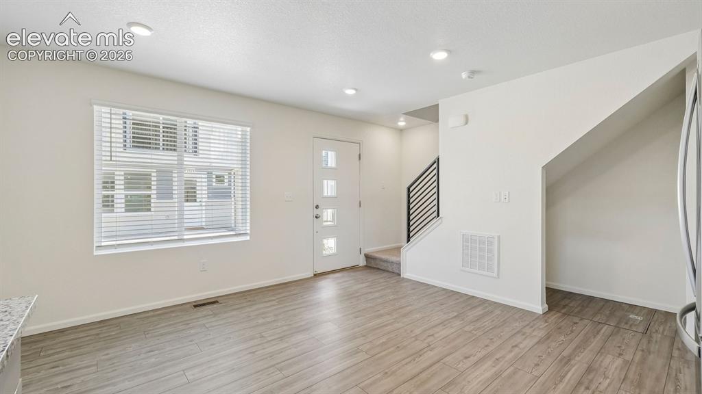 Image 4 of 28: Bright living area featuring wood-finish flooring, recessed lighting, a mod