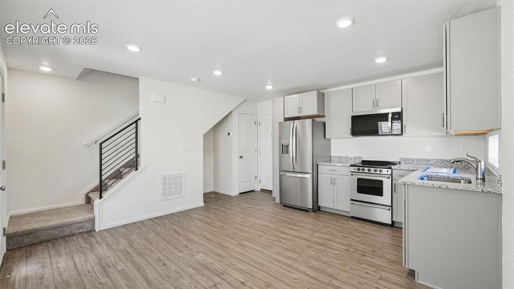 Image 5 of 28: Open-concept living area featuring wood-finish flooring, recessed lighting,