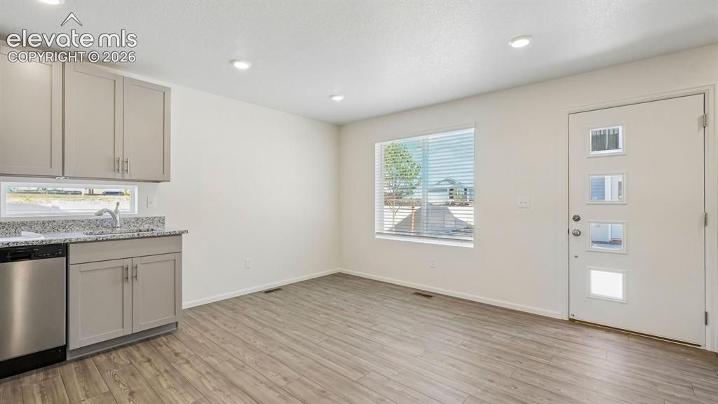 Image 6 of 28: Wood-finish flooring, recessed lighting, and a front entry door with privac
