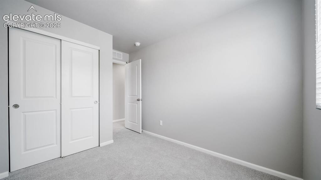 Image 9 of 28: Interior room featuring light gray wall paint, gray carpeting, and white ba