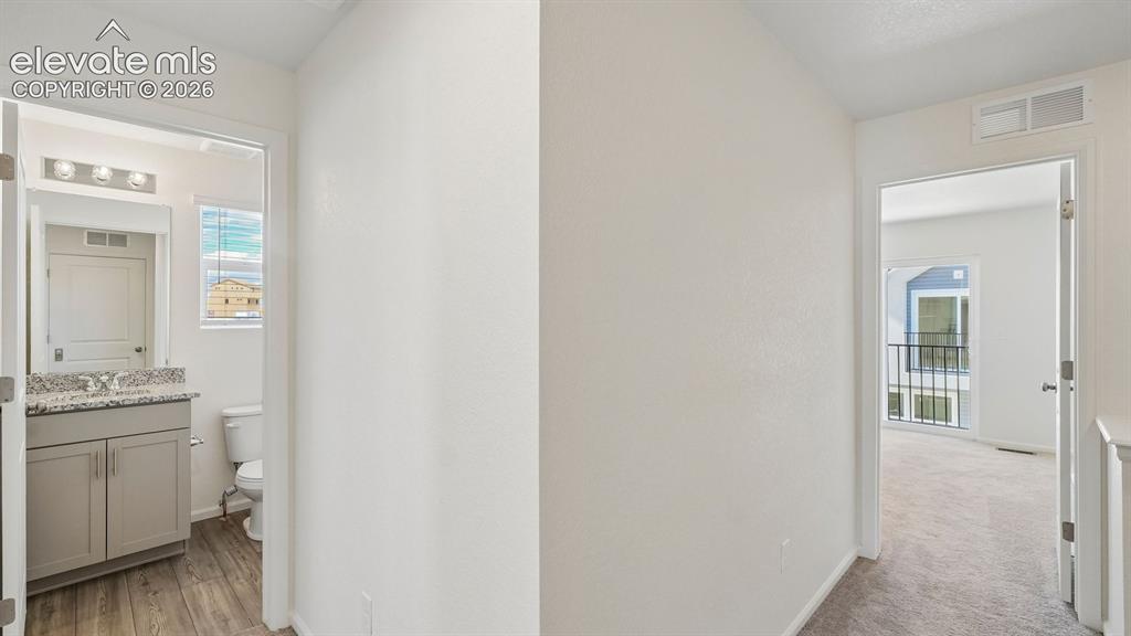 Image 9 of 28: Bathroom featuring a vanity with a light-toned countertop, wood-finish floo