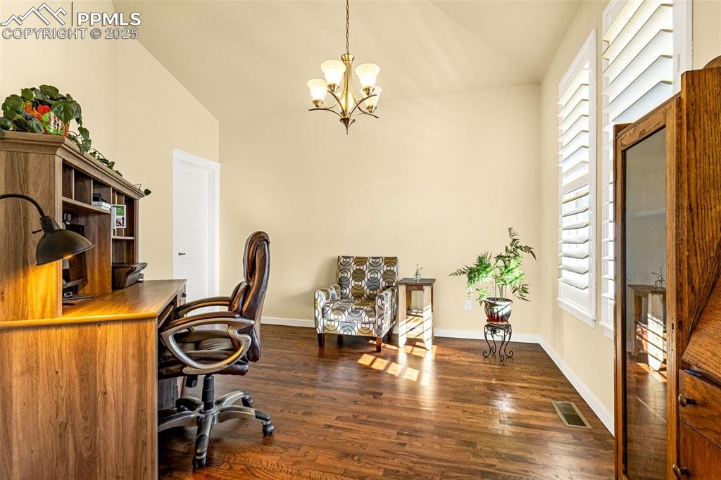 Image 13 of 42: Home office with lofted ceiling, dark wood-type flooring, and an inviting c