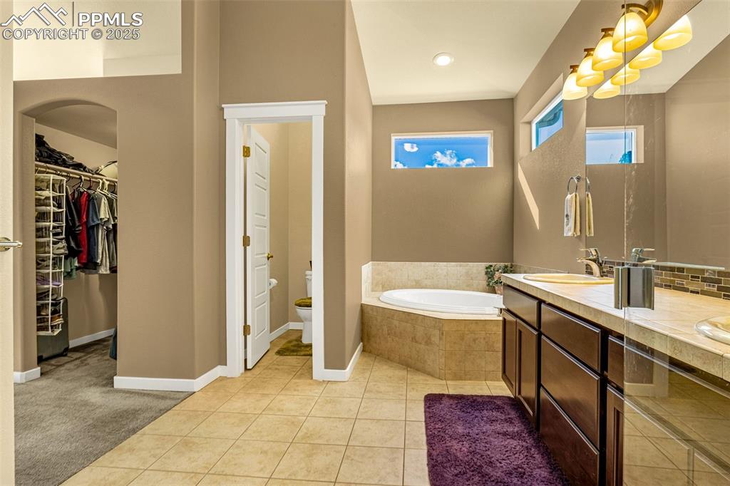 Image 14 of 42: Bathroom featuring tile patterned floors, toilet, vanity, a relaxing tiled
