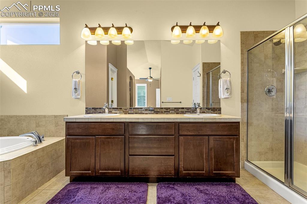 Image 15 of 42: Bathroom with ceiling fan, tile patterned floors, shower with separate bath