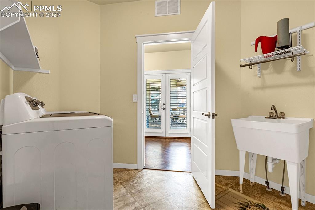 Image 16 of 42: Clothes washing area featuring french doors and separate washer and dryer