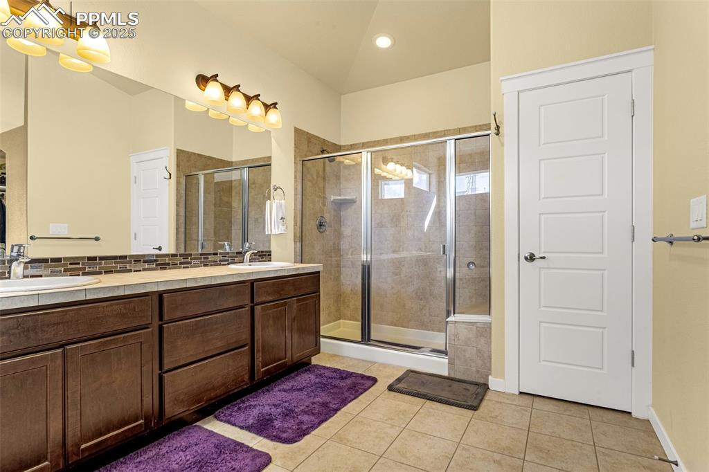 Image 3 of 42: Bathroom featuring tile patterned flooring, vanity, and a shower with door