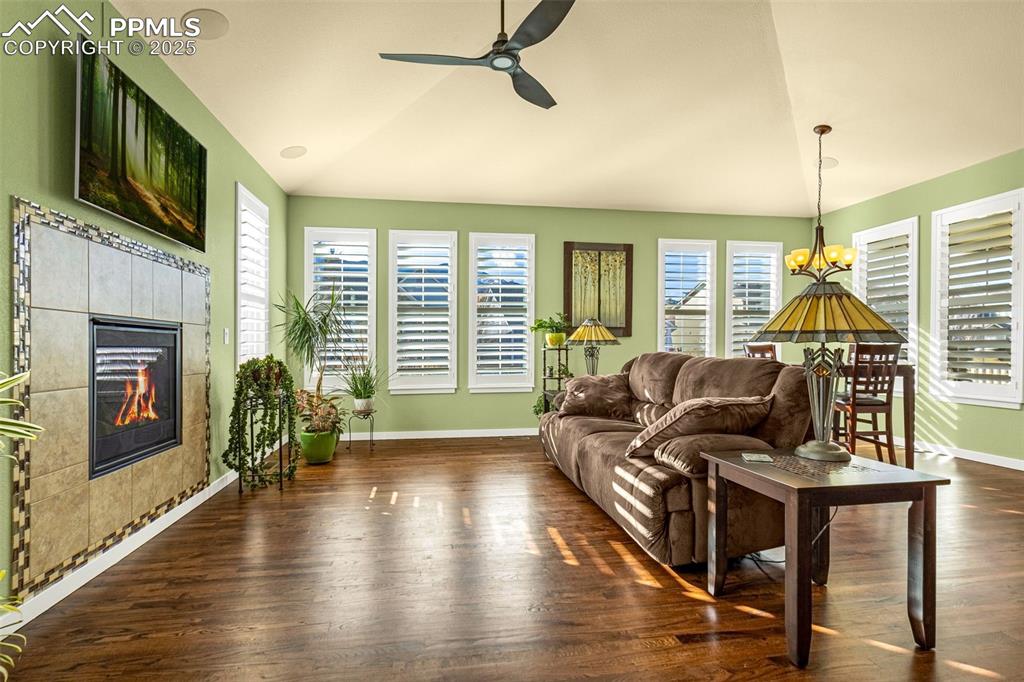 Image 6 of 42: Living room with lofted ceiling, a tiled fireplace, dark wood-type flooring