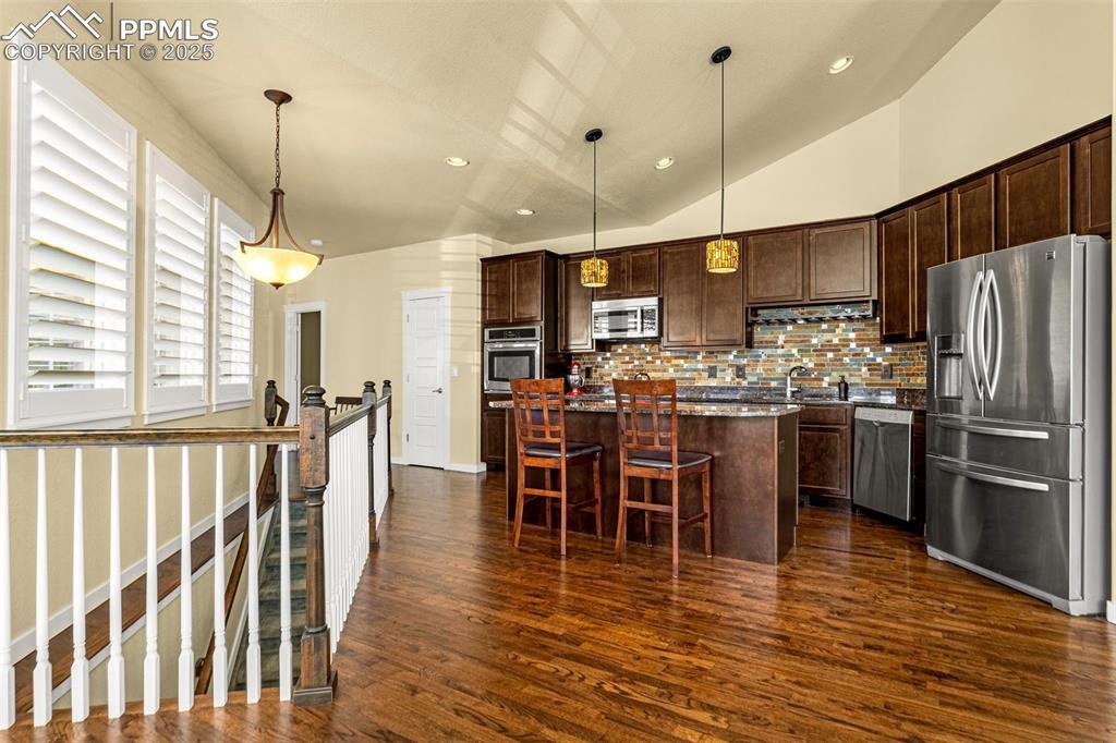 Image 7 of 42: Kitchen featuring hanging light fixtures, appliances with stainless steel f