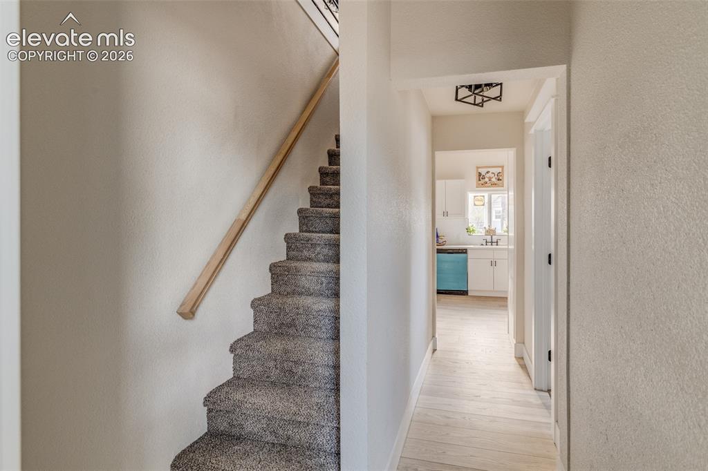 Image 16 of 27: Carpeted staircase with a wood handrail