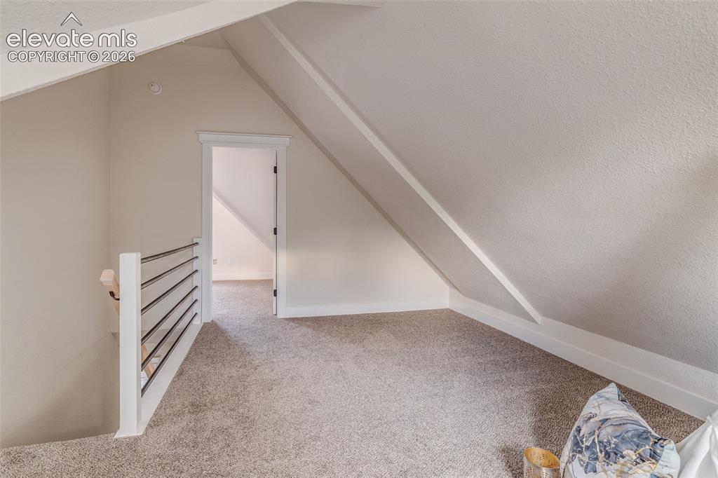 Image 24 of 27: Carpeted loft area featuring a minimalist white and black horizontal railin