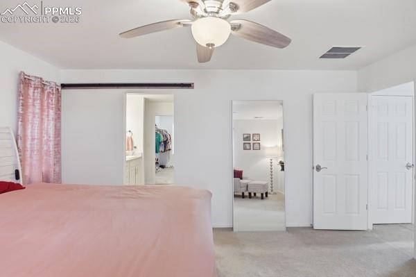 Image 17 of 36: Bedroom featuring light colored carpet, ceiling fan, and ensuite bathroom
