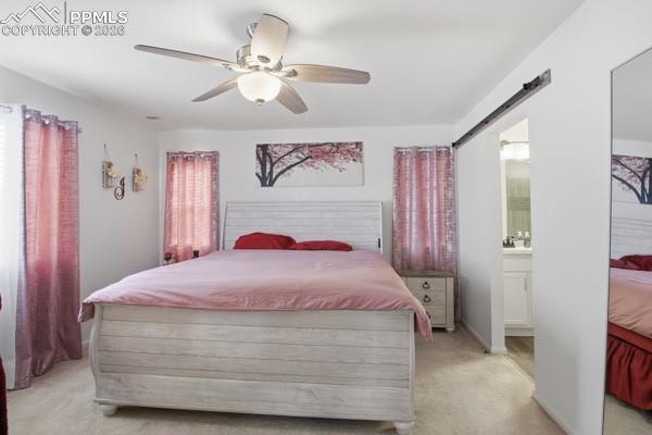 Image 21 of 36: Bedroom featuring light colored carpet, ceiling fan, and ensuite bathroom