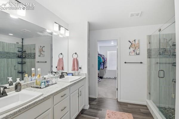 Image 22 of 36: Full bathroom featuring a shower stall, double vanity, a walk in closet, an