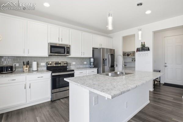 Image 6 of 36: Kitchen with stainless steel appliances, white cabinetry, light countertops