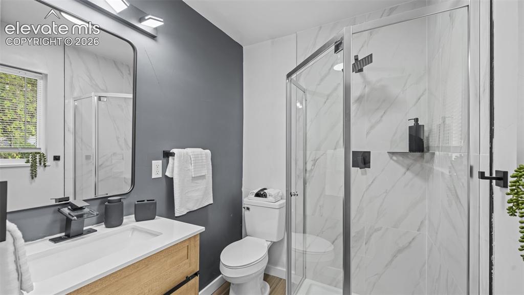 Image 14 of 21: Bathroom featuring a glass-enclosed shower with white marble-look paneling,