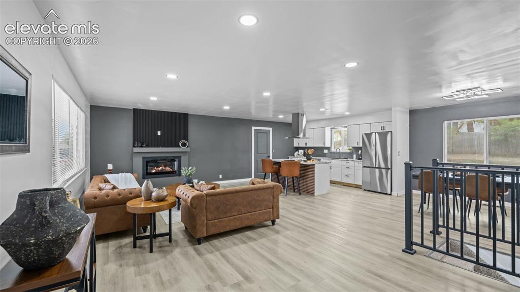 Image 3 of 21: Open-concept living space featuring wood-finish flooring, a contemporary fi