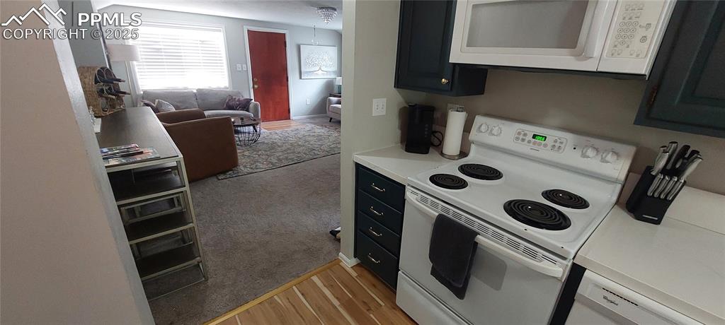 Image 15 of 46: Kitchen featuring white appliances, light countertops, dark cabinetry, open
