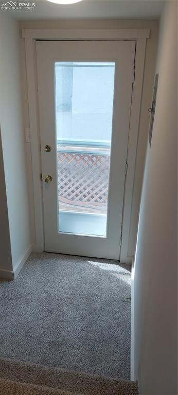 Image 31 of 46: Doorway to outside at rear of home with carpet floors