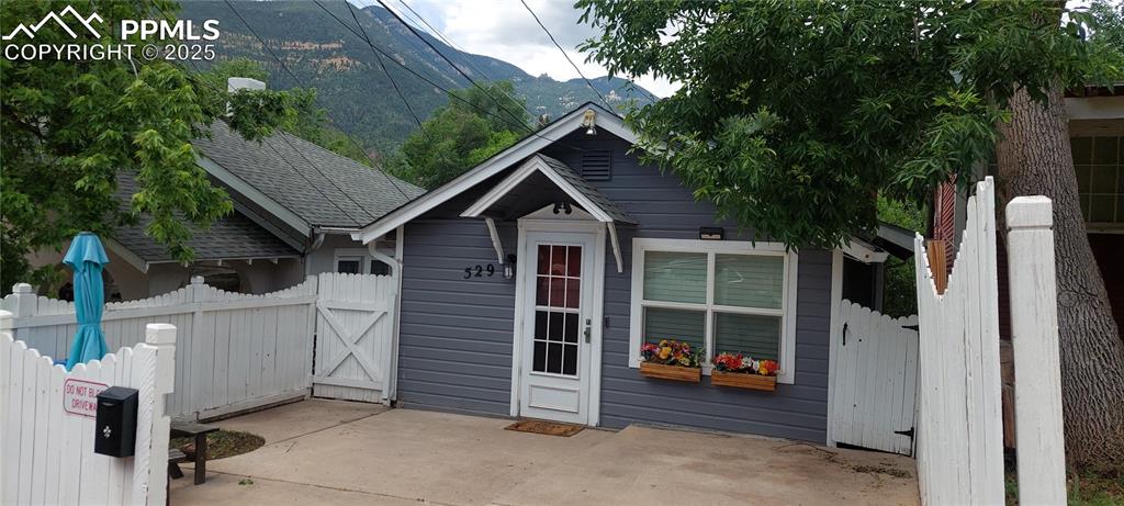 Image 4 of 46: View of front of house featuring a shingled roof, a mountain view, a gate, 