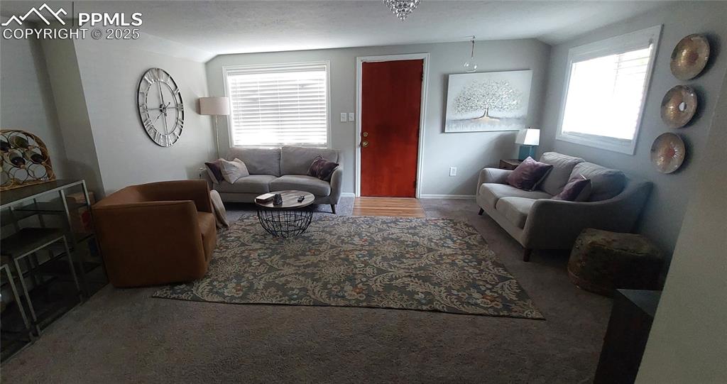 Image 8 of 46: Carpeted living area with healthy amount of natural light and lofted ceilin