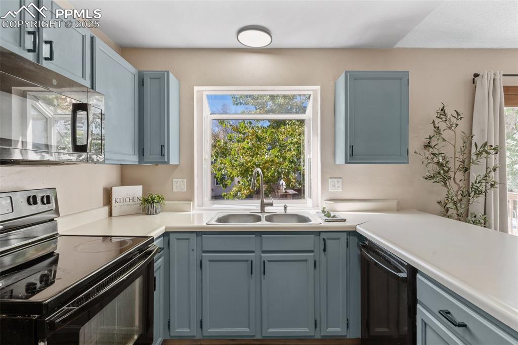 Image 12 of 29: Kitchen with black appliances, light countertops, and gray cabinetry
